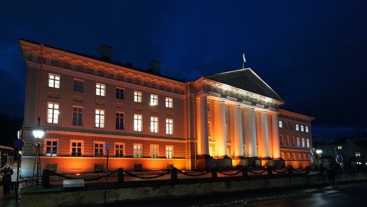 Oranžilt valgustatud Tartu Ülikooli peahoone.