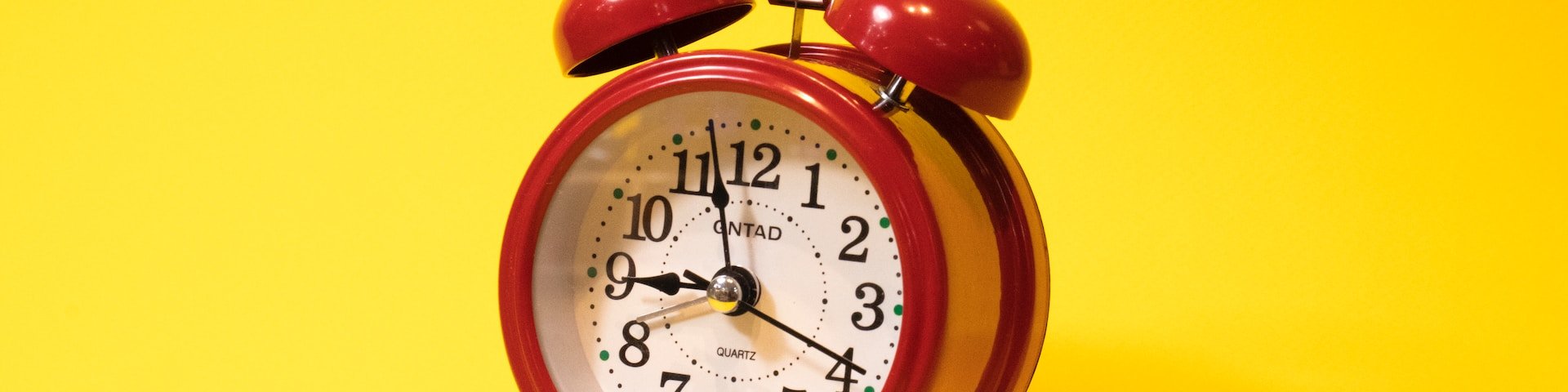 pilt punasest kellast kollasel taustal sümboliseerimaks prokrastineerimist